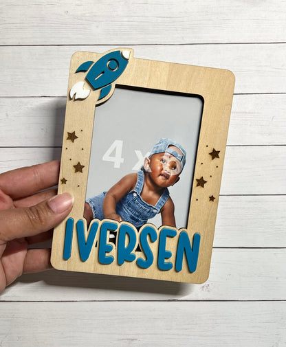 Wooden photo frame with 'IVERSEN' text held by a hand on a light wooden surface